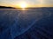 Beautiful sunset scene of Lake Baikal in winter; with texture and quaint pattern of tire tracks on ice surface