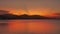 Beautiful sunset on the sea with mountains in the background. Orange tropical sunrise on the ocean against the backdrop