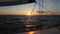 Beautiful sunset at sea shot through the rigging of a sailing yacht boat.