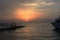 Beautiful sunset on the sea. Wooden piles of destroyed pier sticking out of the water and boat