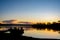 Beautiful sunset on tranquility lake with fishing boat silhouette. Water reflections nature background