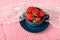 Beautiful, sweet, freshly picked strawberries in a ceramic cup and saucer on a red kitchen tablecloth