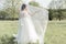 Beautiful sweet girl bride in a gentle air wedding dresses veil in a blooming spring garden in the rays of the sunlight at sunset.