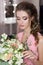 Beautiful sweet girl bridesmaid preparing for the wedding of a friend in the pink evening dress with evening hairstyle and bright