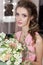 Beautiful sweet girl bridesmaid preparing for the wedding of a friend in the pink evening dress with evening hairstyle and bright