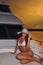 Beautiful swimsuit model wearing white bikini and hat posing on deck of luxury yacht