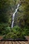 Beautiful tall waterfall flowing over lush green landscape foliage in early Autumn coming out of pages of open story book