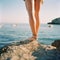 Beautiful tanned female legs on a stone against the backdrop of a beautiful seascape,