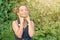 Beautiful tanned happy teen girl listening to music in headphones in nature in the summer.