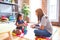 Beautiful teacher and toddler girl playing with construction blocks bulding tower at kindergarten