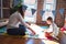 Beautiful teacher and toddler learning maths using numbers puzzle game around lots of toys at kindergarten