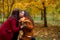Beautiful teen daughter kisses mom. A girl in an orange jacket with luxurious hair. Woman in red with a black coat. Family walk in