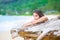 Beautiful teen girl on beach praying by driftwood log