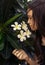 Beautiful teen girl in black tank top with plumeria tree. Boho style portrait.