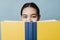 Beautiful Teen Girl Hides Her Smile Behind a Textbook Happy