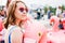 Beautiful teen girl in pink heart shaped glasses on inflatable Flamingo enjoys summer vacation