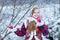 Beautiful teen girl in Russian national clothes with red apples in winter hands