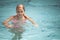 Beautiful teenage blond girl swims in a pool