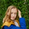 Beautiful teenage blonde schoolgirl in a blue and yellow coat in park in autumn