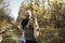 Beautiful teenage couple walking in the forest, laughing and giving someone wooden reed