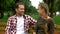 Beautiful teenage daughter telling secrets to father, relaxing on bench in park