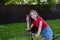 beautiful teenage girl in denim shorts and T-shirt is learning to ride bicycle through streets of summer village on sunny day.