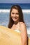 Beautiful Teenage Girl Holding a Surfboard at the Beach Smiling