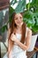 Beautiful teenage girl with long hair in white clothes under leaves