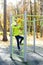 Beautiful teenager daughter in an green jacket plaing on the playground in the autumn park. Horizontal photo