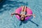 Beautiful teenager girl floating on pink donuts in a pool. Wearing sunglasses and smiling. Fun and summer lifestyle