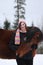 Beautiful teenager girl hugging brown horse in winter