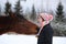 Beautiful teenager girl playfully kissing brown horse in winter