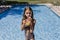 Beautiful teenager girl at the pool drinking healthy orange juice and having fun outdoors. Summertime and lifestyle concept