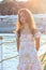 Beautiful teenager girl in the rays of the setting sun on a pier by the sea