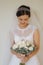 Beautiful and tenderness bride in white dress and veil. Hold bouquet of flowers in hands