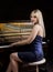 Beautiful thoughtful girl sitting near piano on a dark background