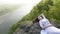 Beautiful and thoughtful young bride in a white wedding dress lying on the rocks alone near the river