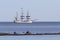 Beautiful three masts sail ship on blue waters near coastline