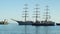 A beautiful three-sailing ship is sailing to the port and it is accompanied by two towing boats in Yalta 4k