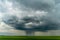 A beautiful thundercloud with rain hovered over a field of wheat. A terrible black cloud on the eve of a tornado and a natural