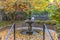 Beautiful tiered fountain on a garden with lush trees and plants in autumn