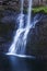 Beautiful tiered waterfall cascading over rocks with a soft ethereal blue tone refection in water