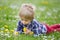 Beautiful toddler blond child, cute boy, lying in the grass in daisy and dandelions filed