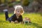 Beautiful toddler boy, eating sweet bread and eggs in garden on sunset, little chicks running around