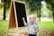 Beautiful toddler boy standing by a blackboard
