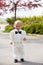 Beautiful toddler boy in tuxedo, playing in a park on a wedding day