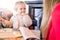 Beautiful toddler child girl sitting on baby highchair  crying front of a woman