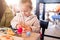 Beautiful toddler child girl sitting on baby highchair  playing with toys on the table