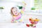 Beautiful toddler girl with curly hair having breakfast