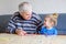 Beautiful toddler girl and grandfather playing together pictures lotto table cards game at home. Cute child and senior